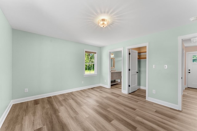 2976 Newmans Neck Rd, Heathsville, VA 22473 - unfurnished bedroom featuring light wood-type flooring, baseboards, a spacious closet, ensuite bathroom, and a closet
