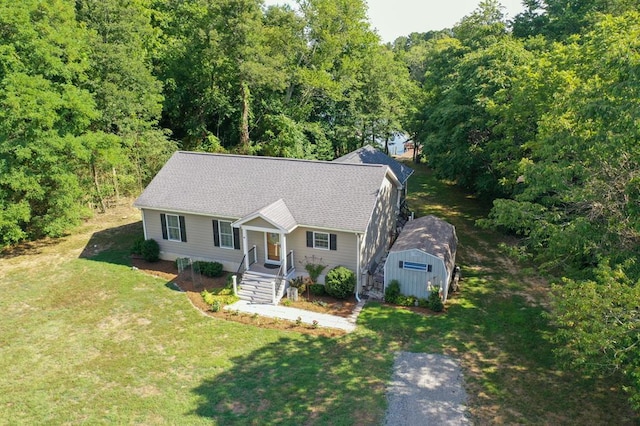 view of front of property featuring an outdoor structure, a front yard, and roof with shingles