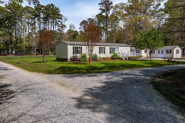 manufactured / mobile home with gravel driveway and a front lawn