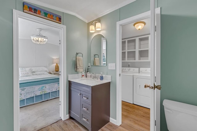 bathroom featuring toilet, washing machine and dryer, wood finished floors, crown molding, and connected bathroom