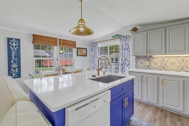 kitchen with lofted ceiling, light countertops, dishwasher, a sink, and light wood-type flooring