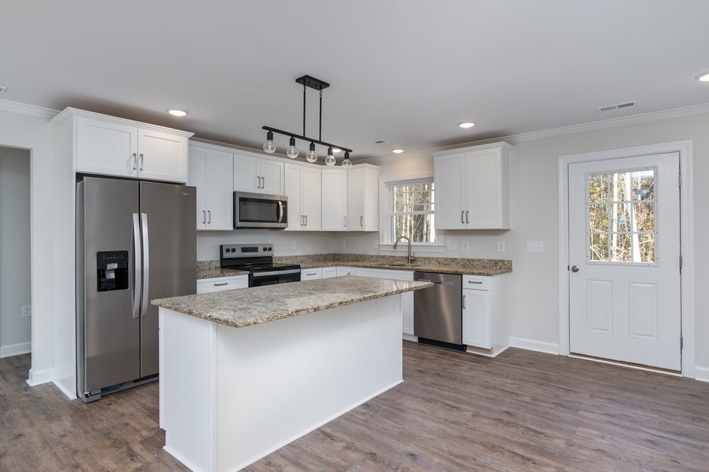 kitchen featuring pendant lighting, stainless steel appliances, white cabinets, and a kitchen island