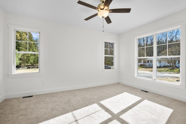 unfurnished bedroom with multiple windows, ceiling fan, light colored carpet, and ensuite bathroom