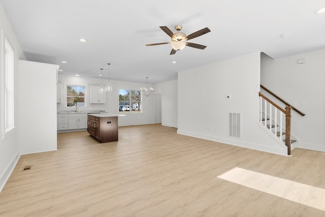 living room with light wood-style flooring, recessed lighting, visible vents, and stairway