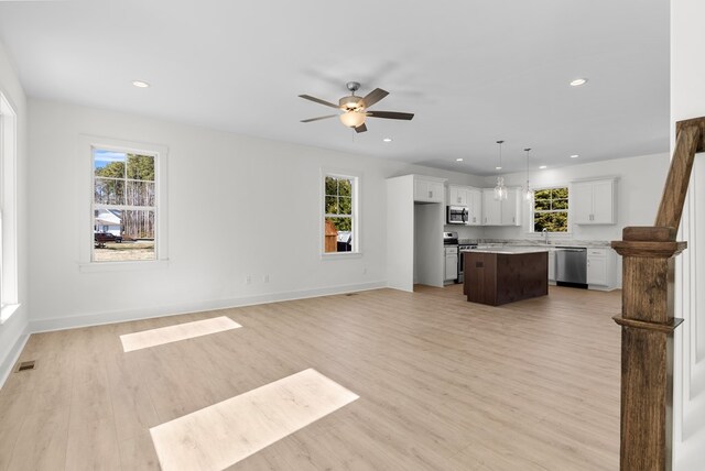 kitchen with white cabinets, pendant lighting, light stone counters, and ceiling fan