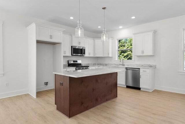 kitchen with white cabinetry, sink, stainless steel dishwasher, and decorative light fixtures