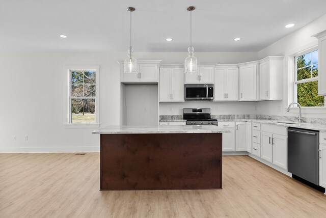 kitchen featuring white cabinets, decorative light fixtures, stainless steel appliances, and a kitchen island