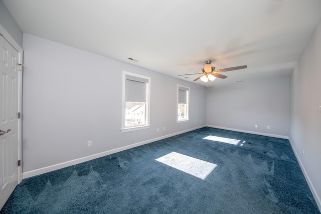 spare room featuring ceiling fan and dark colored carpet