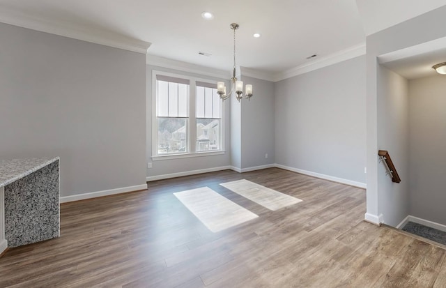 unfurnished dining area with crown molding, hardwood / wood-style floors, and a notable chandelier