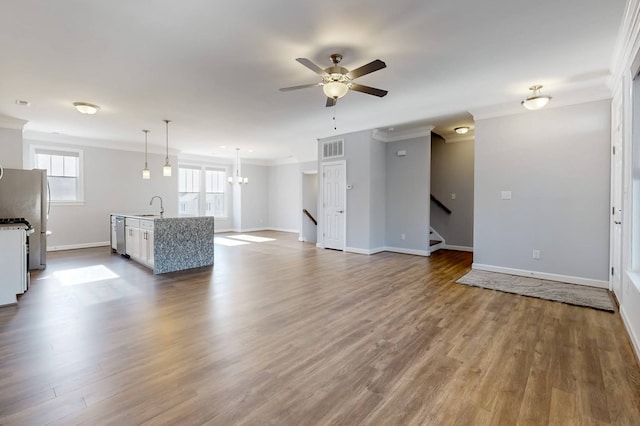 unfurnished living room with hardwood / wood-style flooring, ornamental molding, sink, and ceiling fan