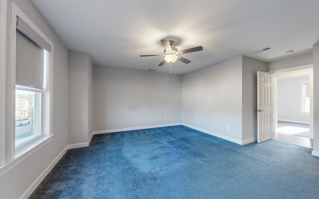 empty room featuring ceiling fan and dark carpet