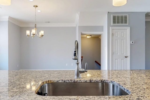 kitchen featuring ornamental molding, light stone countertops, sink, and hanging light fixtures