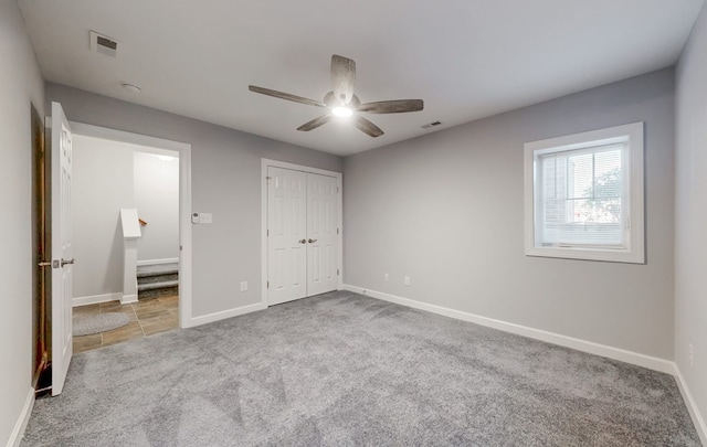 unfurnished bedroom with light colored carpet, ceiling fan, and a closet