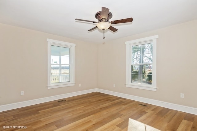 empty room with light wood-style floors, visible vents, ceiling fan, and baseboards