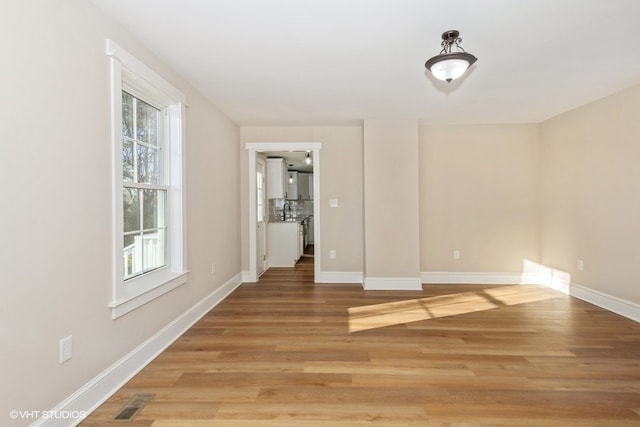 unfurnished dining area featuring a sink, baseboards, and wood finished floors