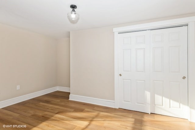 unfurnished bedroom with a closet, baseboards, and wood finished floors