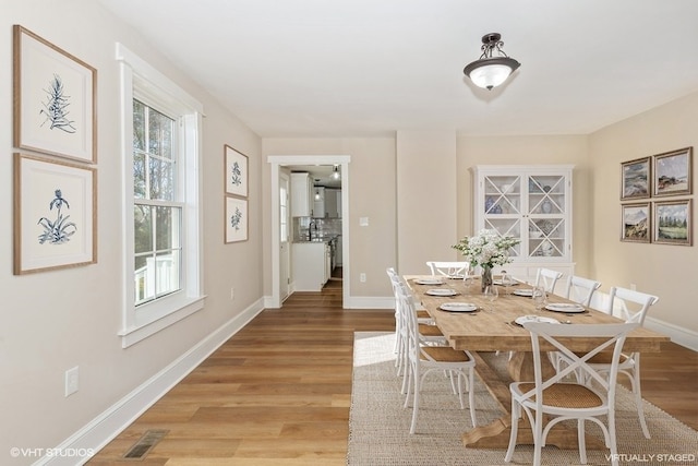 dining area with visible vents, light wood-style flooring, and baseboards