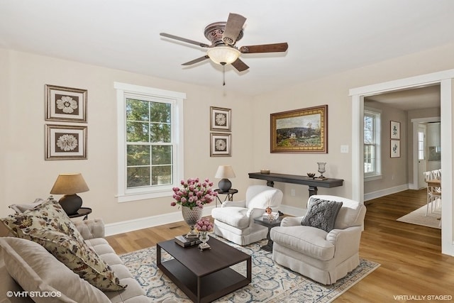 living room featuring light wood-type flooring, baseboards, and a ceiling fan