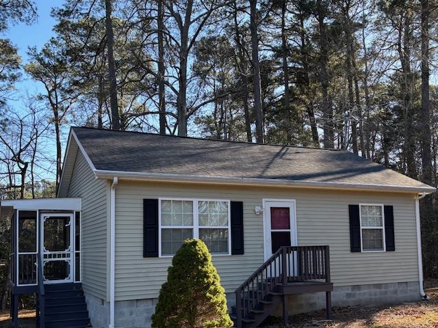 view of front of house with crawl space, a sunroom, and roof with shingles