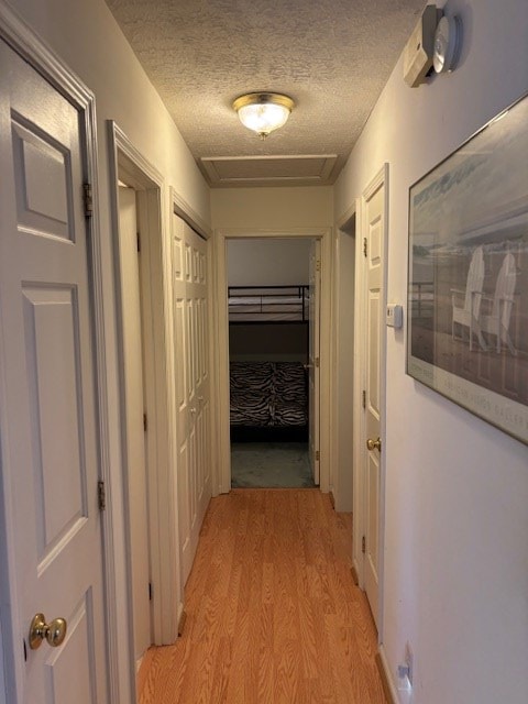 hallway featuring light wood-style floors and a textured ceiling