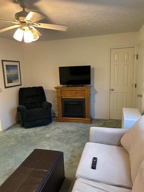 carpeted living room featuring a textured ceiling, a fireplace, a ceiling fan, and baseboards