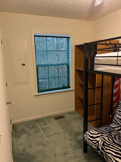 unfurnished bedroom with visible vents, a textured ceiling, carpet flooring, and electric panel