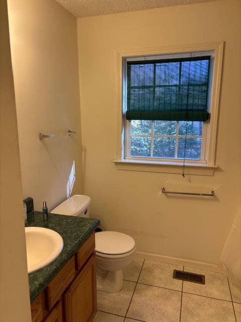 half bath with visible vents, toilet, a textured ceiling, vanity, and tile patterned floors