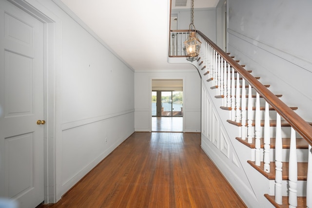 stairway with wood-type flooring and ornamental molding