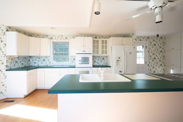 kitchen with white cabinetry, sink, white appliances, and light wood-type flooring