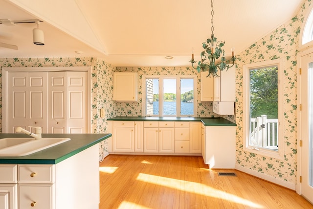 kitchen featuring light hardwood / wood-style floors, vaulted ceiling, white cabinetry, and sink