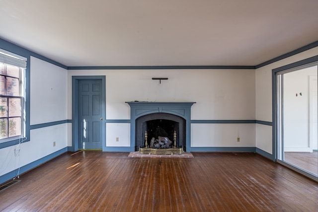 unfurnished living room featuring plenty of natural light, crown molding, and dark wood-type flooring