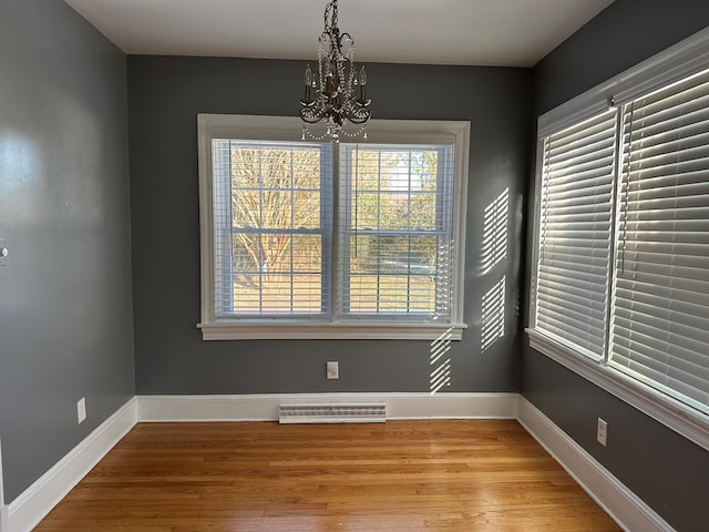 unfurnished dining area featuring an inviting chandelier and light hardwood / wood-style flooring