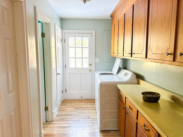 washroom with light hardwood / wood-style floors, washing machine and dryer, and cabinets