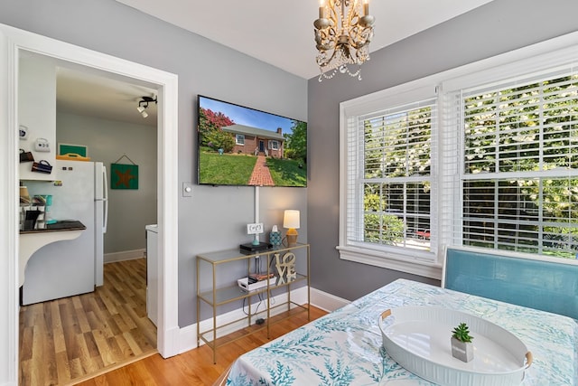 bedroom featuring white fridge, hardwood / wood-style floors, and a notable chandelier