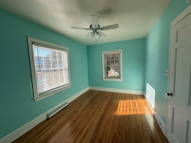 unfurnished room featuring a baseboard heating unit, dark hardwood / wood-style floors, and ceiling fan