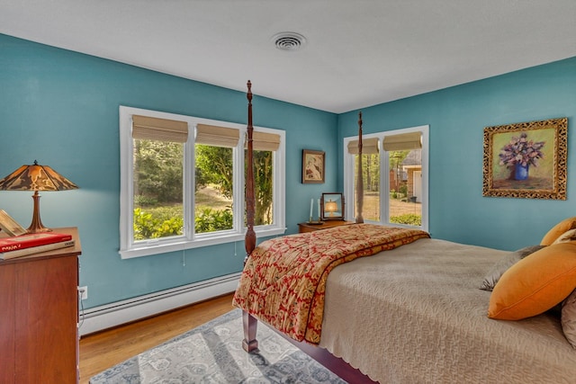 555 Rio Vis, Weems, VA 22576 - bedroom featuring visible vents, baseboard heating, and wood finished floors