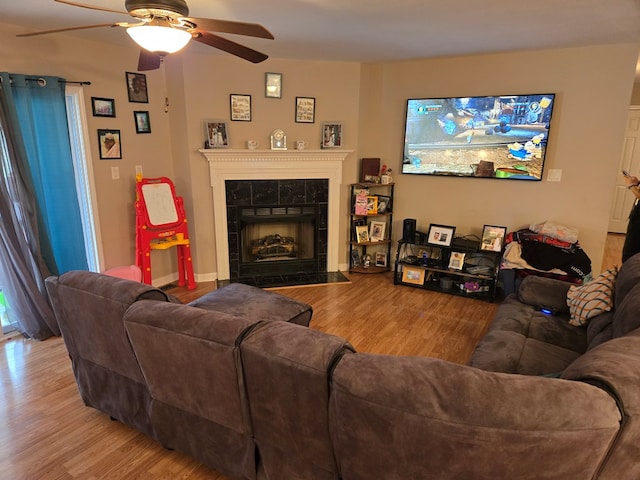 living room with ceiling fan, a tile fireplace, and light hardwood / wood-style flooring