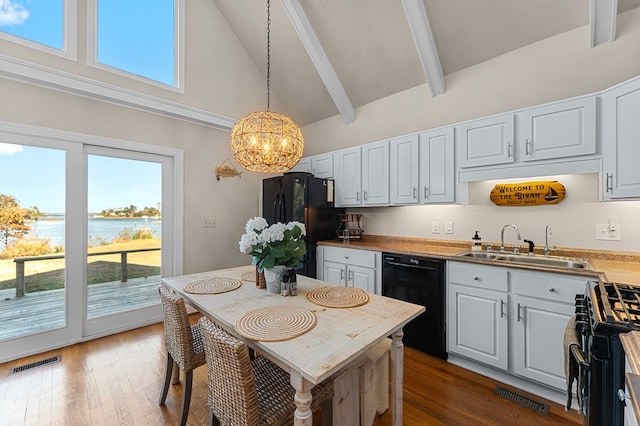 kitchen featuring black appliances, a water view, beamed ceiling, decorative light fixtures, and white cabinetry