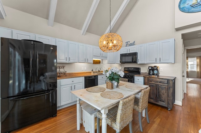 kitchen with black appliances, beam ceiling, white cabinets, and pendant lighting