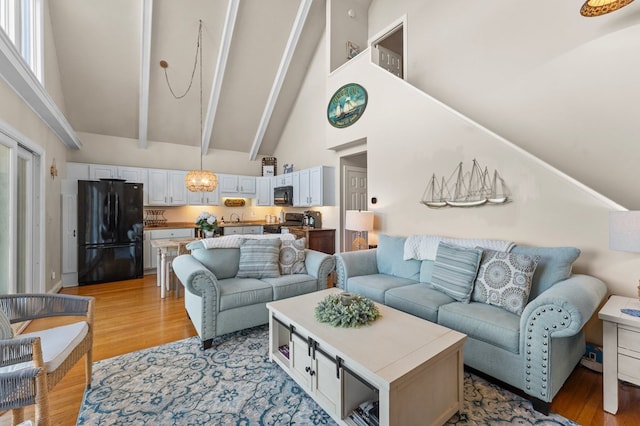 living room with beamed ceiling, light hardwood / wood-style floors, and high vaulted ceiling