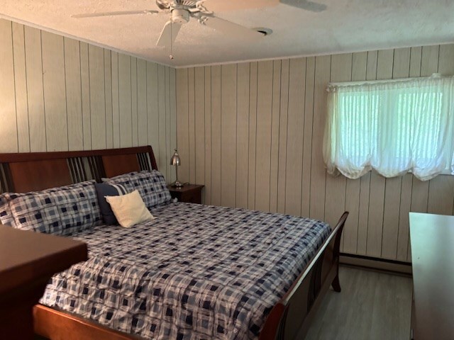 890 Gordon Way, Montross, VA 22520 - bedroom with wood finished floors, ceiling fan, and wooden walls