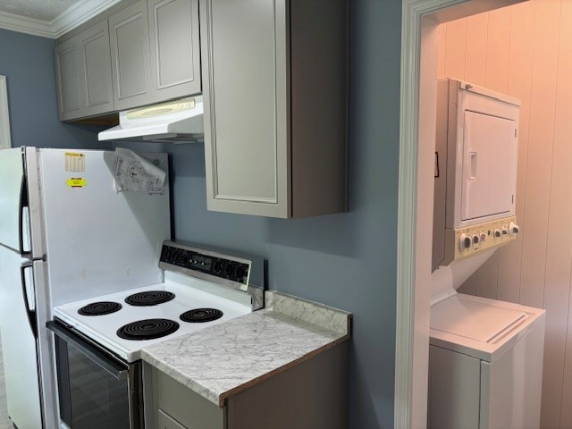 890 Gordon Way, Montross, VA 22520 - kitchen with electric range, stacked washer / drying machine, under cabinet range hood, light countertops, and crown molding