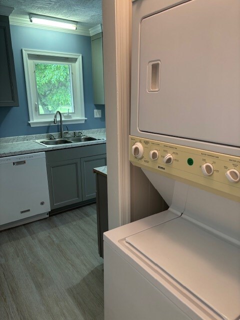 890 Gordon Way, Montross, VA 22520 - washroom with stacked washer / dryer, a sink, a textured ceiling, light wood-style flooring, and crown molding