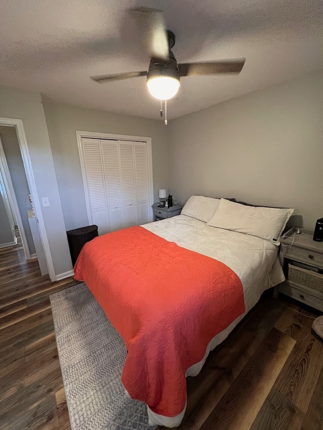 bedroom featuring a textured ceiling, a closet, ceiling fan, and dark wood-type flooring