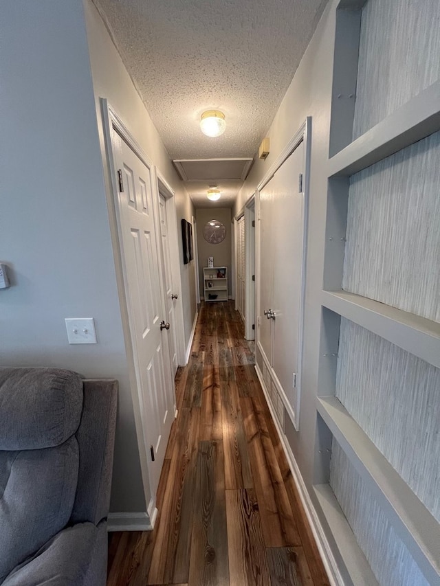 hall featuring built in features, dark hardwood / wood-style flooring, and a textured ceiling