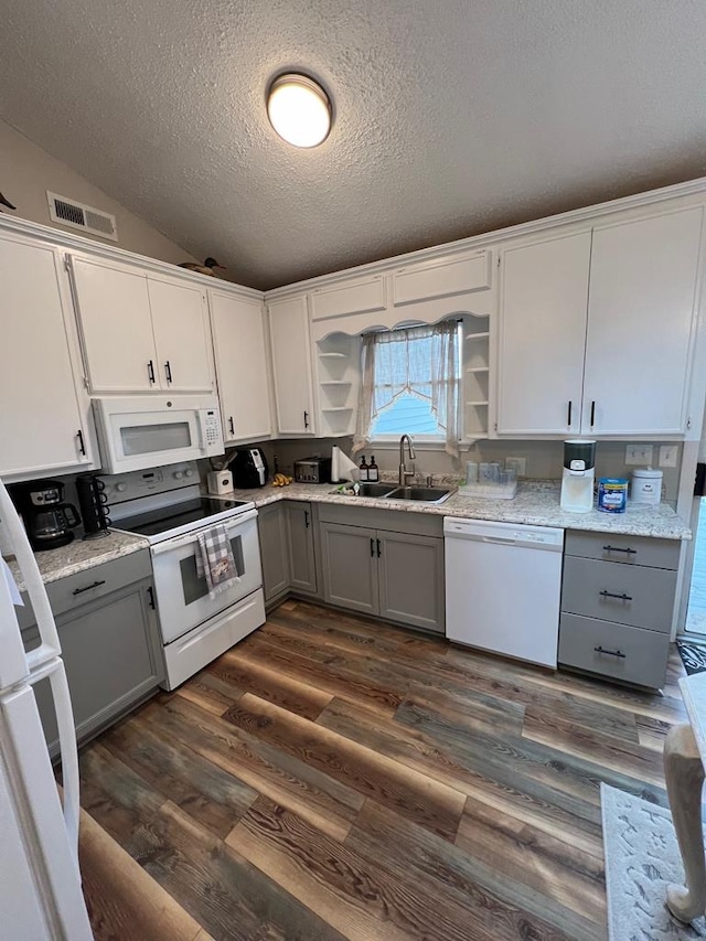 kitchen with sink, a textured ceiling, vaulted ceiling, white appliances, and gray cabinets