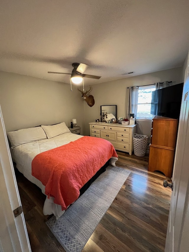 bedroom with ceiling fan, dark hardwood / wood-style flooring, and a textured ceiling