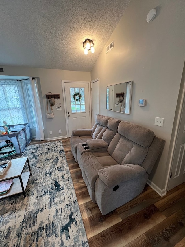 living room with dark hardwood / wood-style flooring, a textured ceiling, and vaulted ceiling