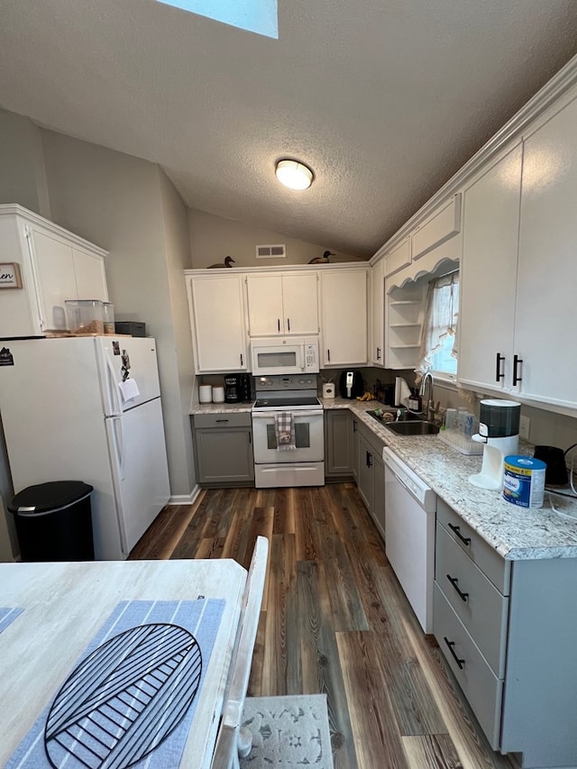 kitchen featuring vaulted ceiling with skylight, white cabinetry, white appliances, and sink