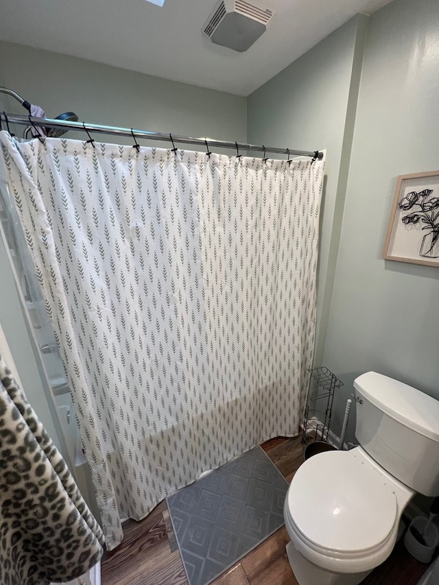 bathroom with toilet, wood-type flooring, and walk in shower